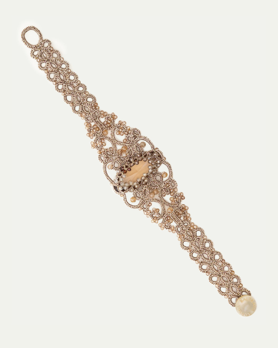 Gold silk bracelet with pearl, crystal detailing, intricate woven texture, highlight on central pearl embellishment.