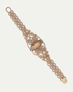 Gold silk bracelet with pearl, crystal detailing, intricate woven texture, highlight on central pearl embellishment.