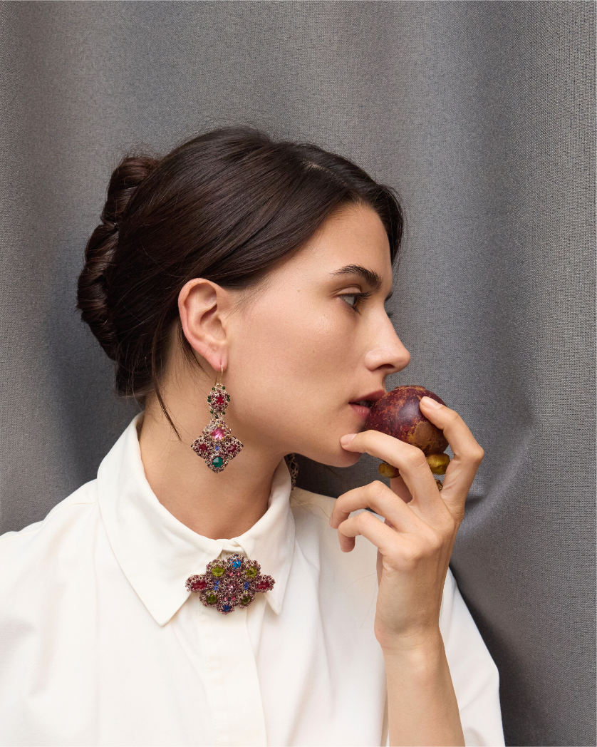 Elegant multicolored gemstone drop earrings with intricate metalwork, complementing a white blouse.