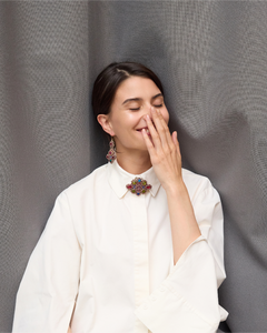 Silk earrings in vibrant colors showcased against a textured gray background with detailed craftsmanship.