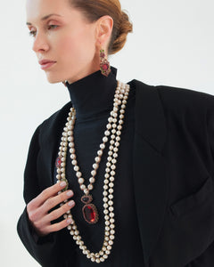 Red garnet pendant with freshwater pearls, silk thread, worn with black attire, elegant detailed design.