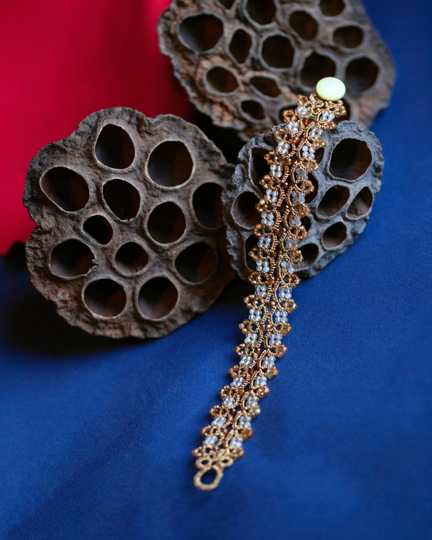 Gold Sophie bracelet with intricate woven design, pearl accents, and elegant side view on dark backdrop.