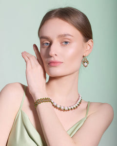 Green beaded bracelet and pearl necklace on wrist, side view, with matching beaded pearl earrings.