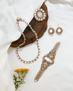 ZINOVIA BROOCH with pearls, multicolor gems, ornate gold detailing, placed on wooden surface, elegant side view.